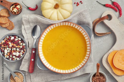Pumpkin, mixed beans and sweet potato creme soup in ceramic bowl, top view with ingredients and spices