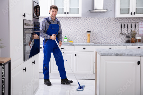 Happy Janitor Cleaning Floor With Mop © Andrey Popov