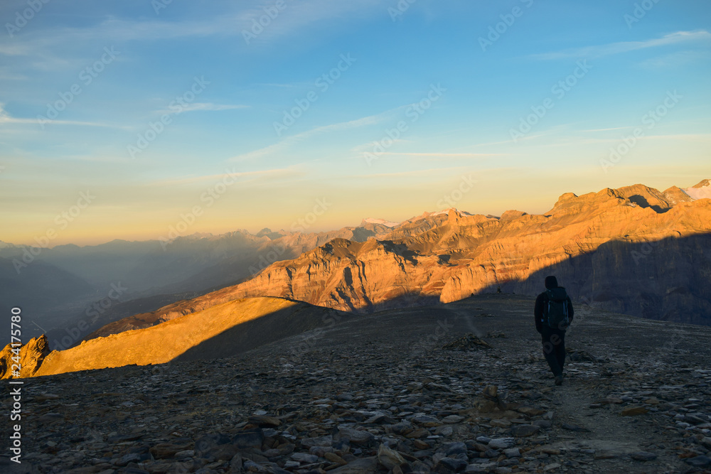 Hiker on the 3000m high Torrenthorn with a beautiful sunrise, Switzerland/Europe