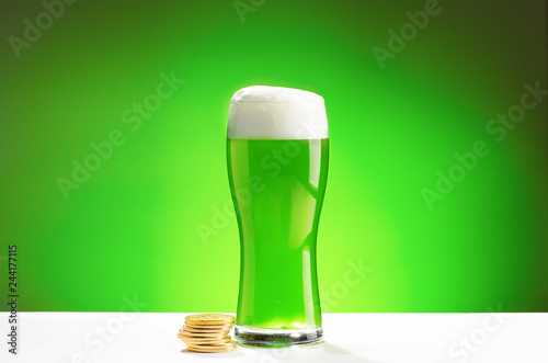 Glass of fresh cold green beer on a wooden bar counter in pub.