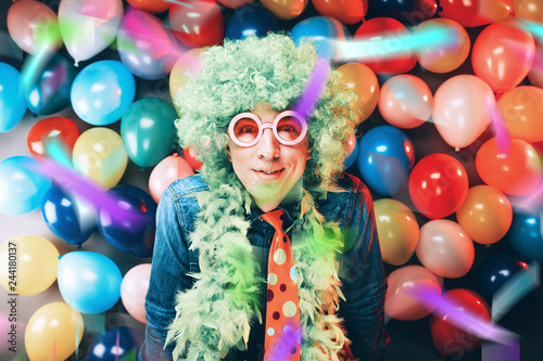 Mann in Karnevalsstimmung auf buntem Hintergrund aus Lüftballons.party Konzept