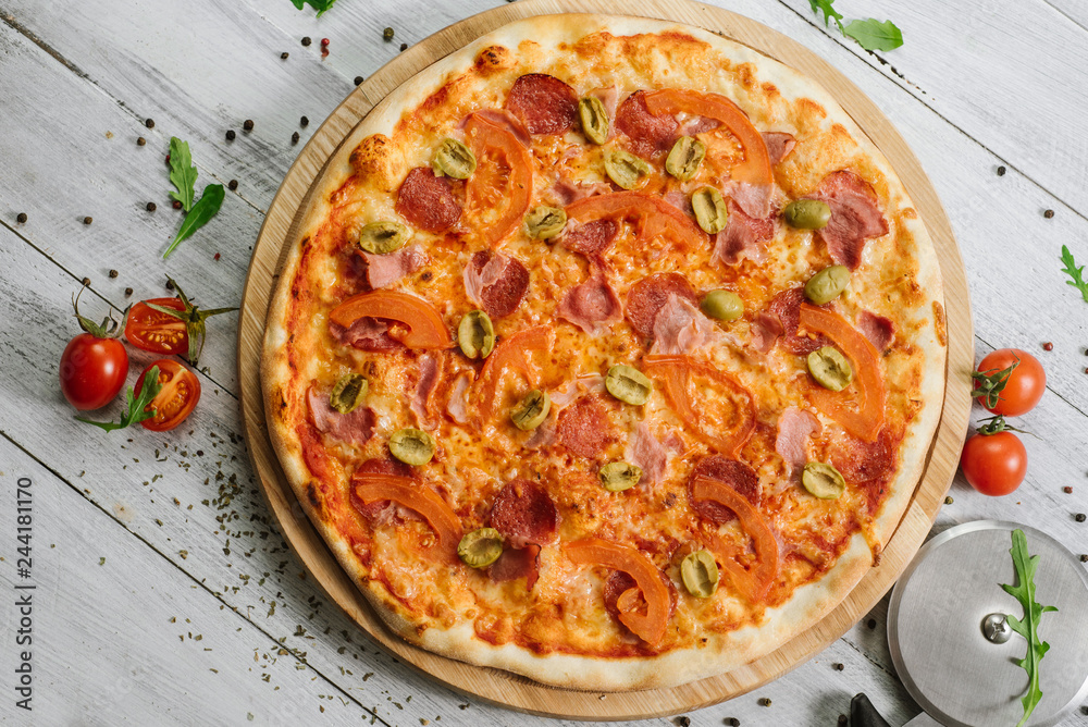 Tasty pizza Chachatore with mozzarella, salami and olives on the white wooden background
