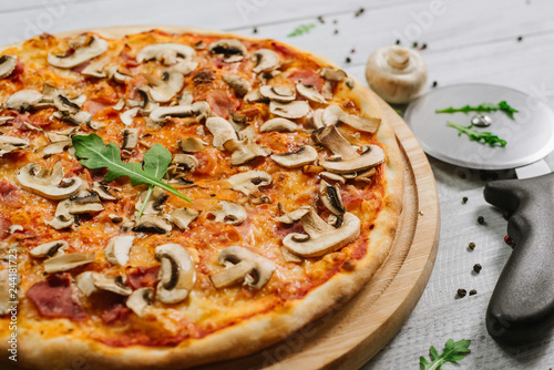 Tasty pizza Caprizzioza with tomato sauce  ham and champignons on the white wooden background