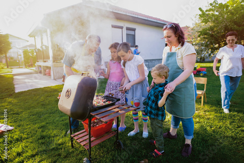 Young girl learning how to make a barbeque while their mother is watching them.