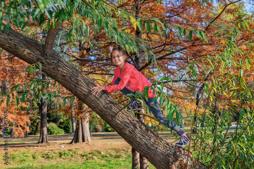 Smiling girl climbing tree outdoors on the park