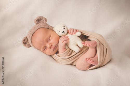 Newborn sleeping boy with a toy in a hat with ears