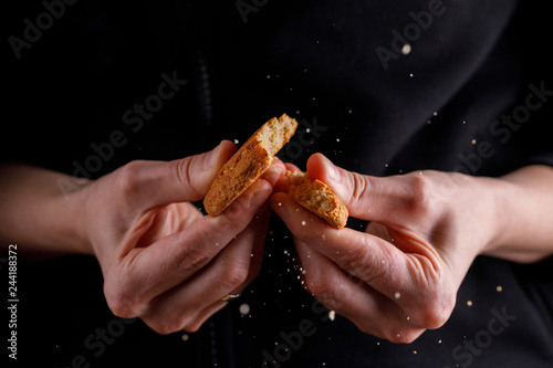 Cookies breaking in the hands on a dark background.
