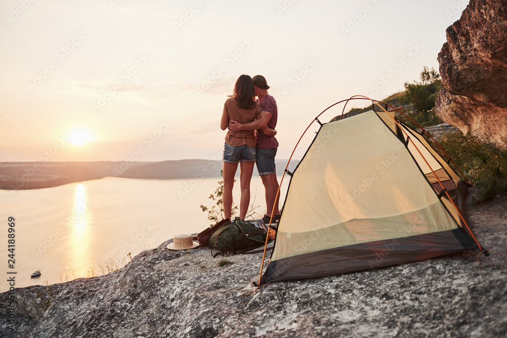 Fototapeta premium Photo of happy near tent with a view of lake during hiking trip. Travel Lifestyle adventure vacations concept