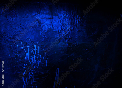 White paint dripping on a dark blue wall. Grunge background.