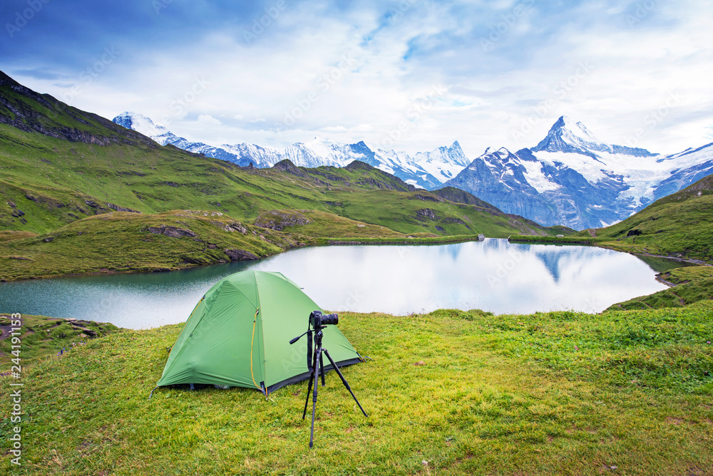 Tent and camera on a tripod in the mountains in the Swiss Alps, Europe (still life coach, company, friendship, background - concept)