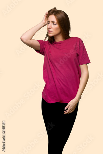 Young redhead girl having doubts while scratching head on isolated yellow background