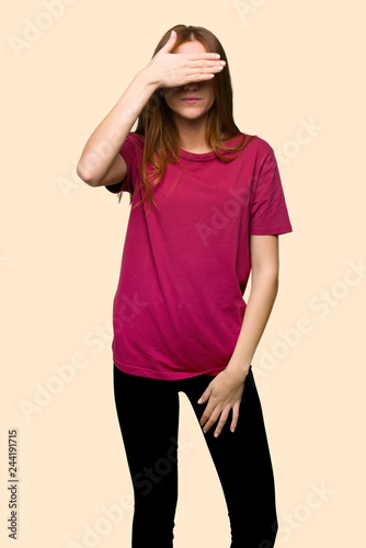 Young redhead girl covering eyes by hands. Do not want to see something on isolated yellow background