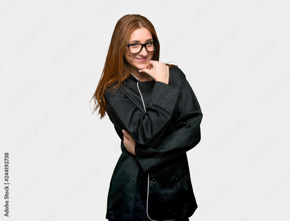 Young redhead chef woman with glasses and smiling on isolated grey background Young redhead chef woman with glasses and smiling on isolated grey background