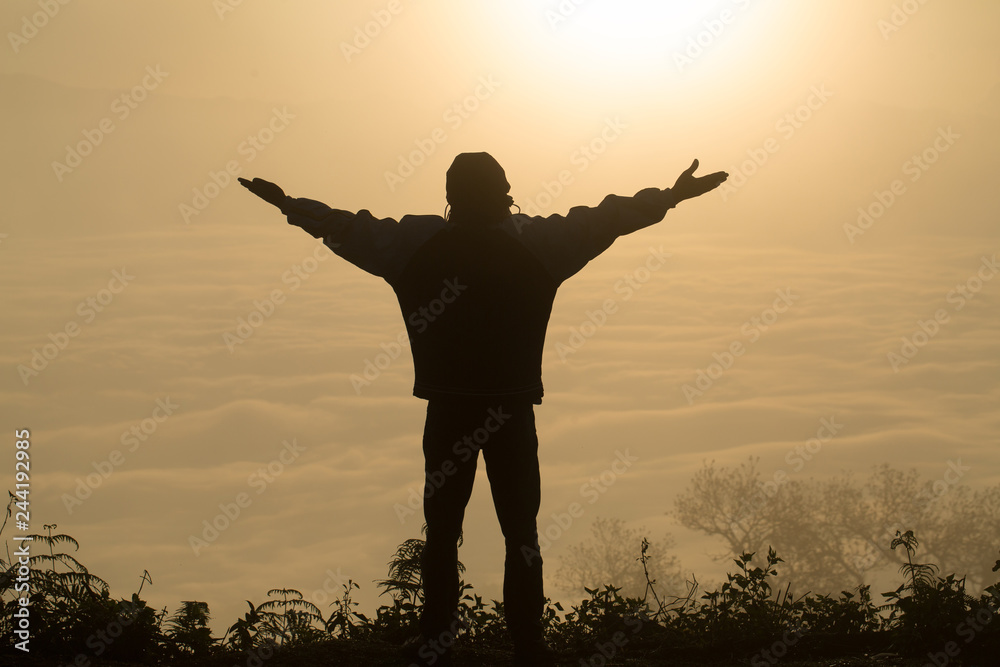 Fototapeta premium Man praying at sunset mountains raised hands Travel Lifestyle spiritual relaxation emotional concept, Freedom and travel adventure.