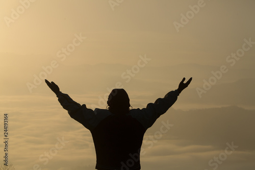 Man praying at sunset mountains raised hands Travel Lifestyle spiritual relaxation emotional concept, Freedom and travel adventure.