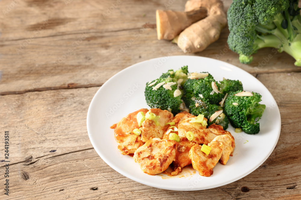 chicken breast fillet and broccoli with ginger on a rustic wooden board, copy space
