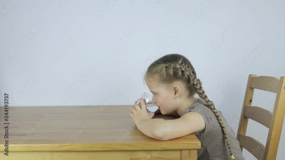 Little girl drinks water from a glass while Little girl drinks water from a glass while