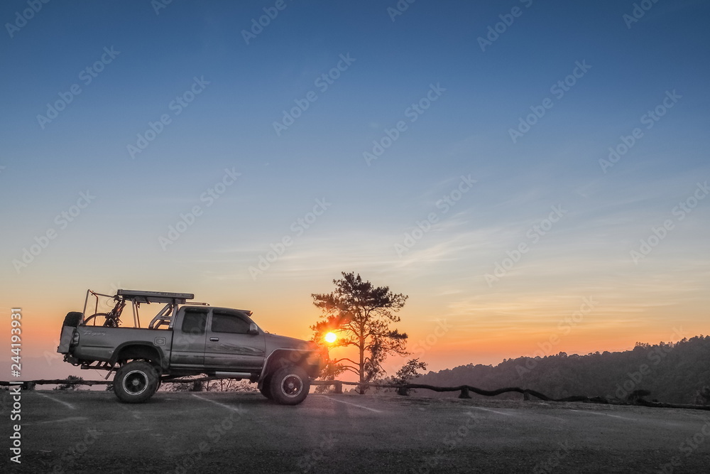 sunset at Huai Nam Dang National Park, beautiful silhouette of a 4x4 truck parking on the road with colorful red light in the sky background, Huai Nam Dang in Chiang Mai, northern of Thailand.