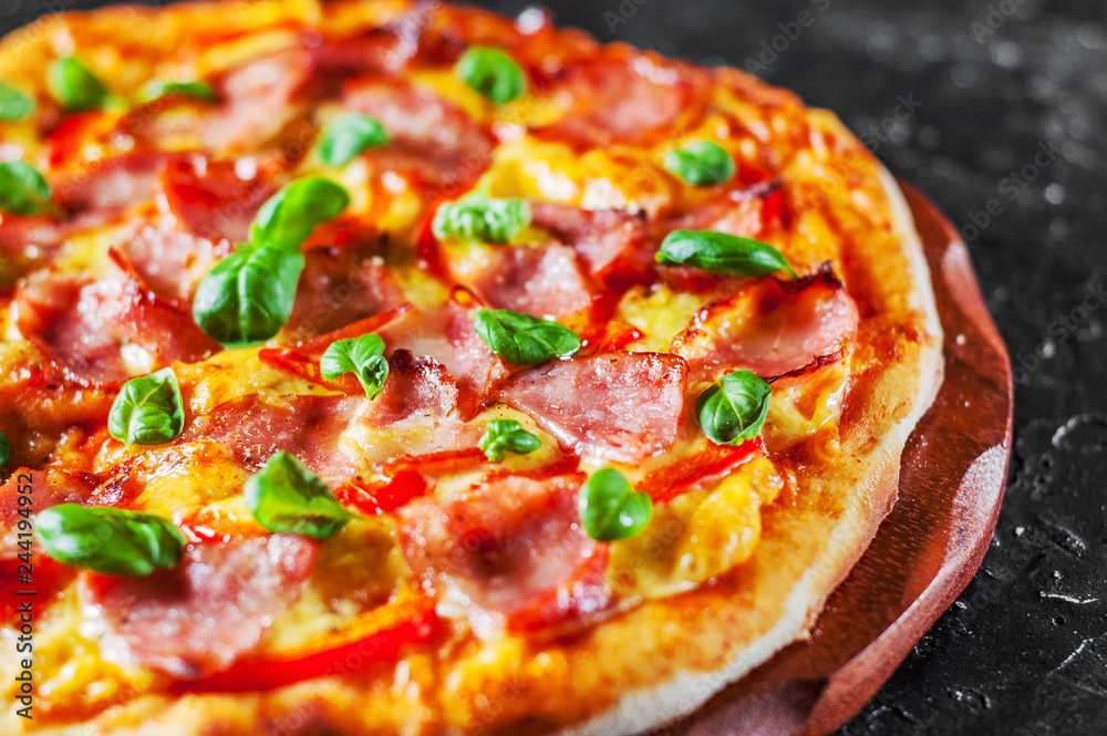 Pizza with Mozzarella cheese, ham, pepper, meat, Tomato sauce, Spices and Fresh Basil. Italian pizza on black background