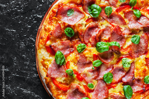 Pizza with Mozzarella cheese, ham, pepper, meat, Tomato sauce, Spices and Fresh Basil. Italian pizza on black background