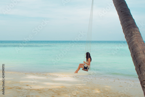 Swing on a palm tree. Beautiful island landscape with relaxing girl on a swing.