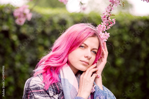 young beautiful girl with pink hair standing near a tree with flowers, pink flowers, spring, sun, happiness