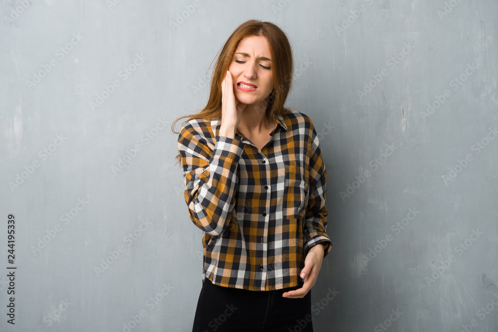 Young redhead girl over grunge wall with toothache Young redhead girl over grunge wall with toothache