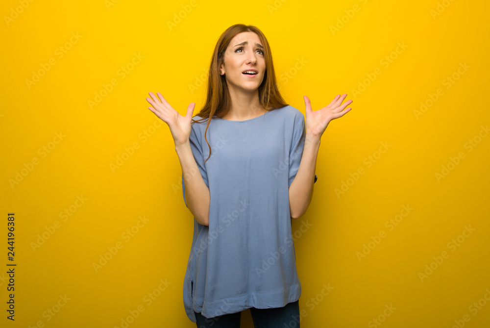 Young redhead girl over yellow wall background frustrated by a bad situation Young redhead girl over yellow wall background frustrated by a bad situation