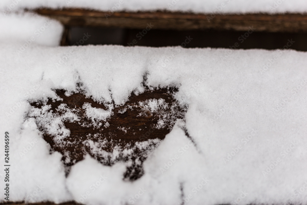 Heart drawn in the snow on a wooden bench, close up view. Valentine's day greeting card with place for text. Heart drawn in the snow on a wooden bench, close up view. Valentine's day greeting card with place for text.