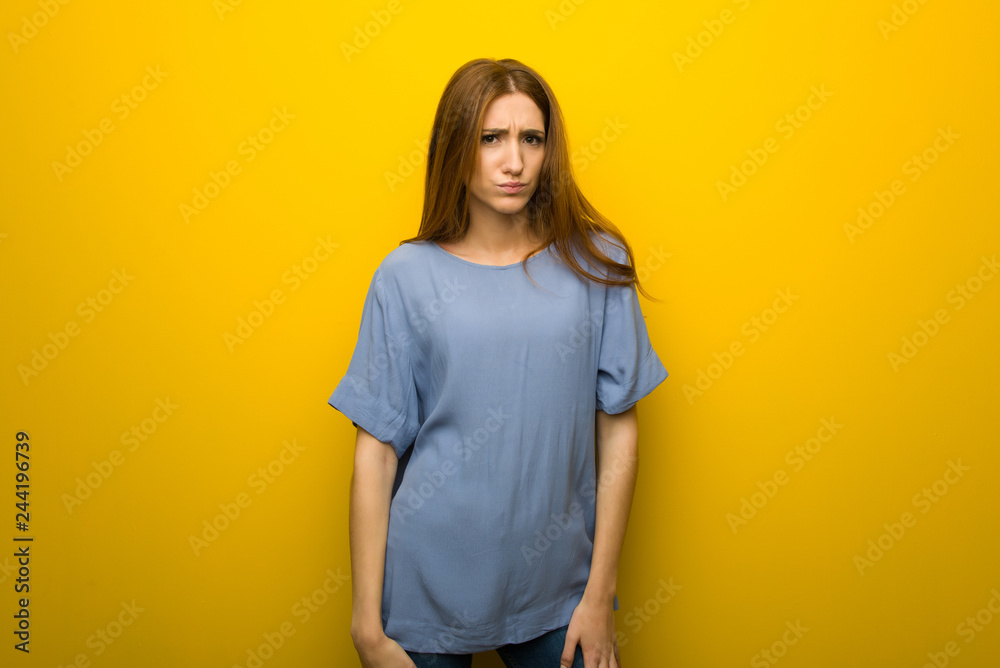 Young redhead girl over yellow wall background with sad and depressed expression Young redhead girl over yellow wall background with sad and depressed expression