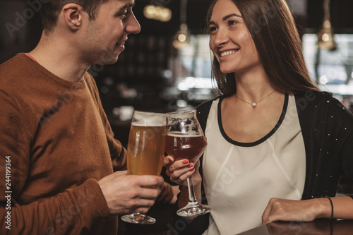 Cropped shot of a happy loving couple clinking their beer glasses  smiling at each other. Cheerful man and his beautiful girlfriend having drinks at the bar  celebrating Valentines Day. Love  couples 