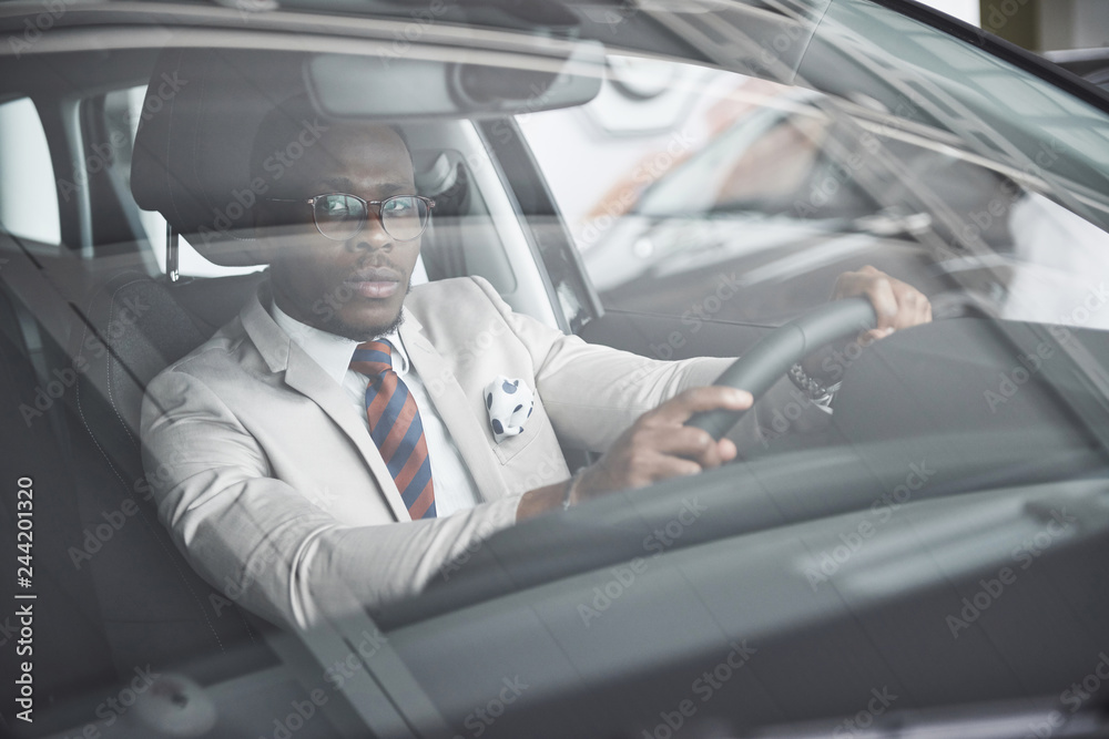 front view of Handsome african elegant serious business man drives a car