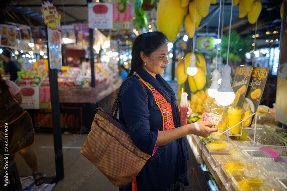 Mature beautiful Indian woman buying mango fruits in market Mature beautiful Indian woman buying mango fruits in market