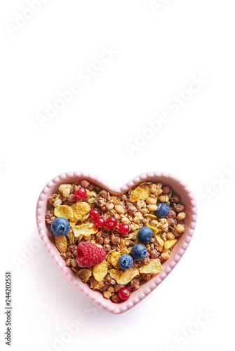 Cereals with fruits in a hart shaped bowl isolated on a white background viewed from above. Top view. Copy space. Healthy, fresh, home made corn flakes breakfast