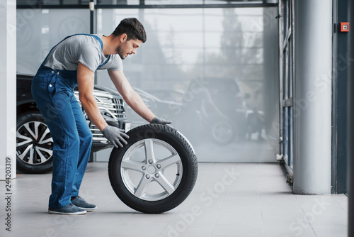 Mechanic holding a tire tire at the repair garage. replacement of winter and summer tires © standret