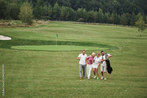 Group of stylish friends on the golf course learn to play a new game. The team is going to rest after the match
