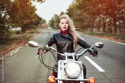 A stylish biker woman posing outdoor with motorcycle. 