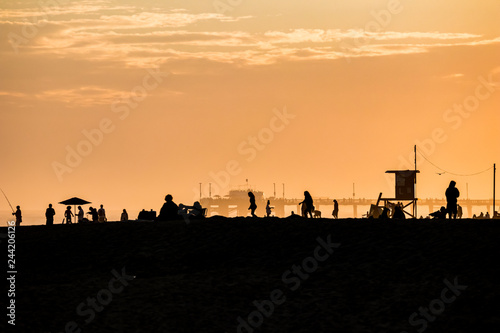 Silhouettes of people and pier on a beach during sunset in Newport Beach california