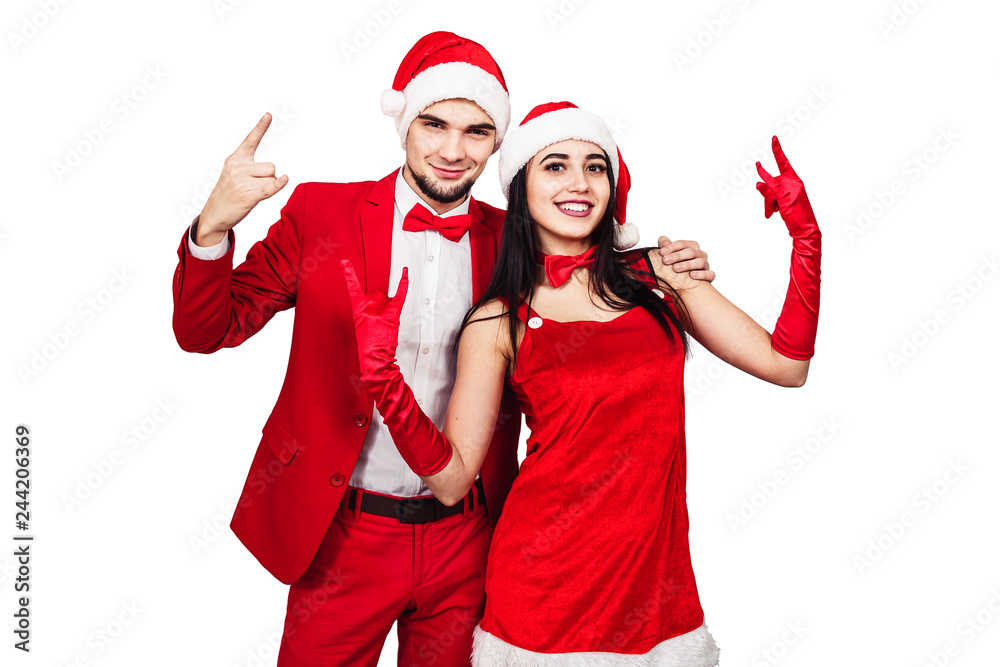 young couple having fun at a christmas theme party. young man and woman in red suits with Santa hats young couple having fun at a christmas theme party. young man and woman in red suits with Santa hats