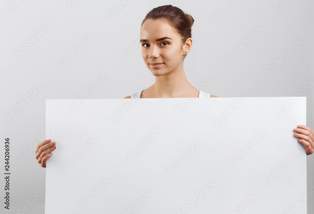 Portrait of a beautiful brunette woman holding a white blank banner. Portrait of a beautiful brunette woman holding a white blank banner.