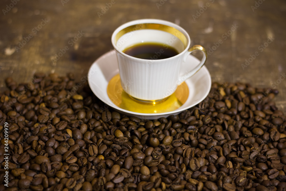 Fototapeta premium cup of coffee with beans on wooden table