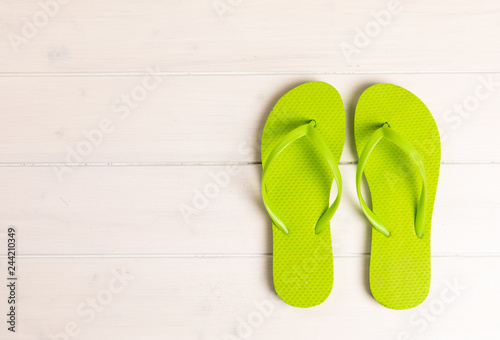 green flip flops on white wooden background with copy space