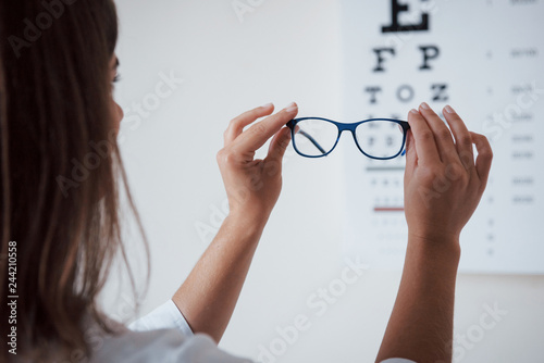 Photo from behind. Woman looking through the glasses eye chart