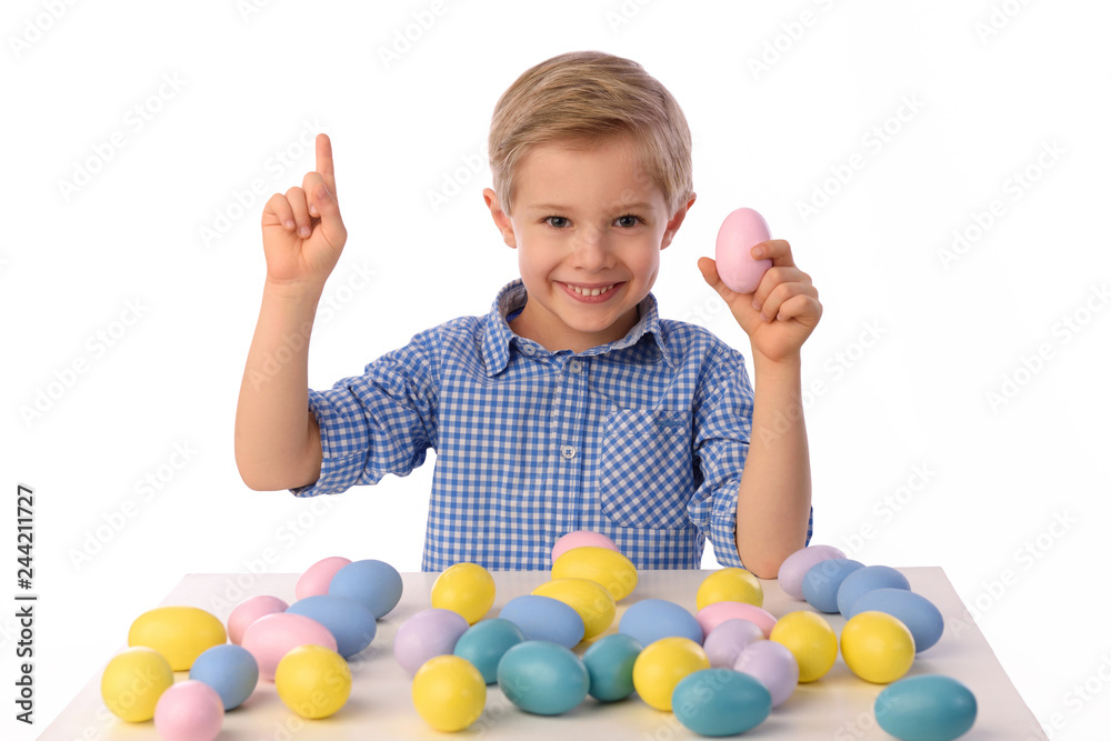 The child is painting eggs for Easter day. Nice, smiling boy sitting at a table with colorful eggs in baskets, yellow chicks. Happy Easter. Isolated on a white. The child is painting eggs for Easter day. Nice, smiling boy sitting at a table with colorful eggs in baskets, yellow chicks. Happy Easter. Isolated on a white.