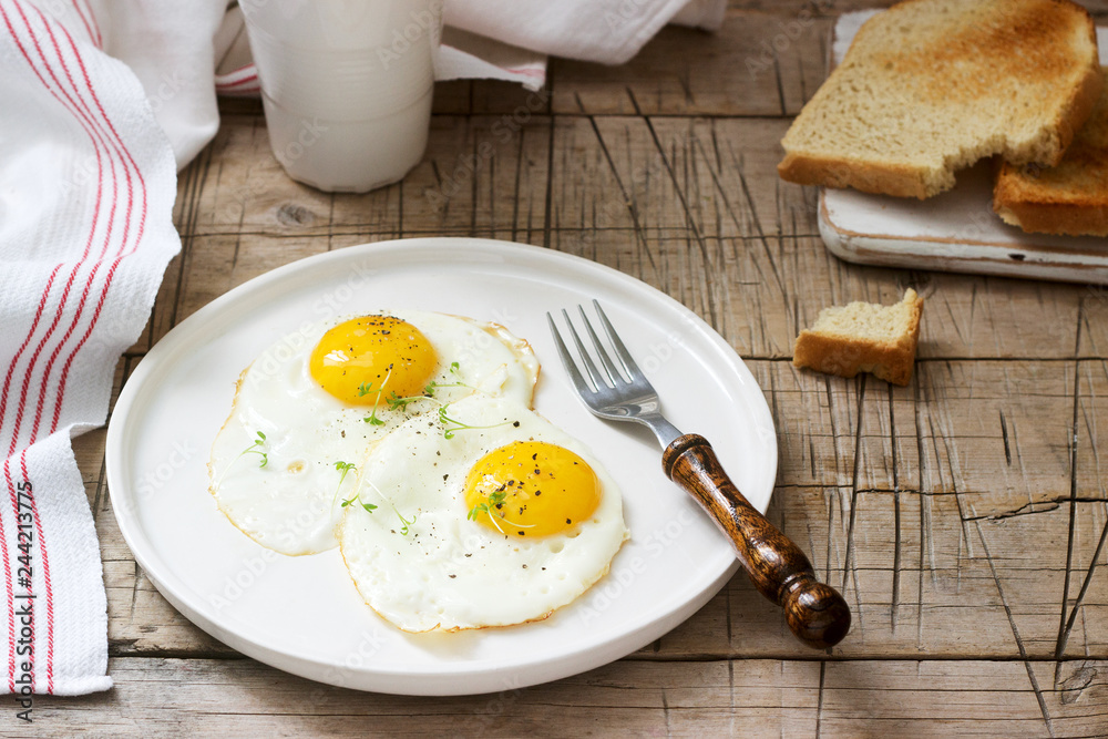 Breakfast of fried eggs, bread toasts and coffee on a wooden table. Rustic style. Breakfast of fried eggs, bread toasts and coffee on a wooden table. Rustic style.