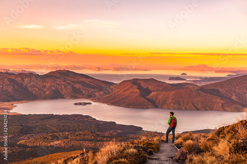 Hiking wanderlust adventure man hiker alone looking at sunset nature landscape of mountains and lakes during summer. Travel outdoors freedom lifestye. photo
