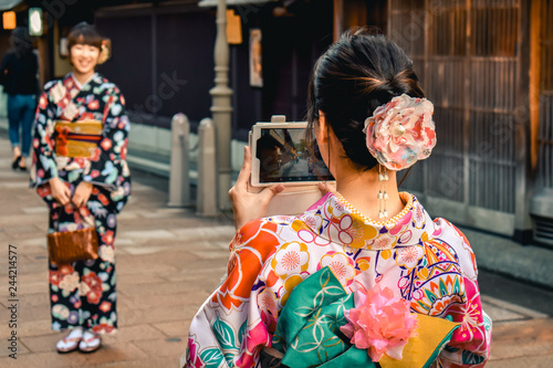Japanese girls in Kimono's taking photos of each other on a cell phone in the Kanazawa old town in Japan