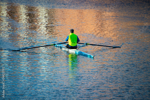 man in yellow vest trains on a racing sculling boat in Oxford
