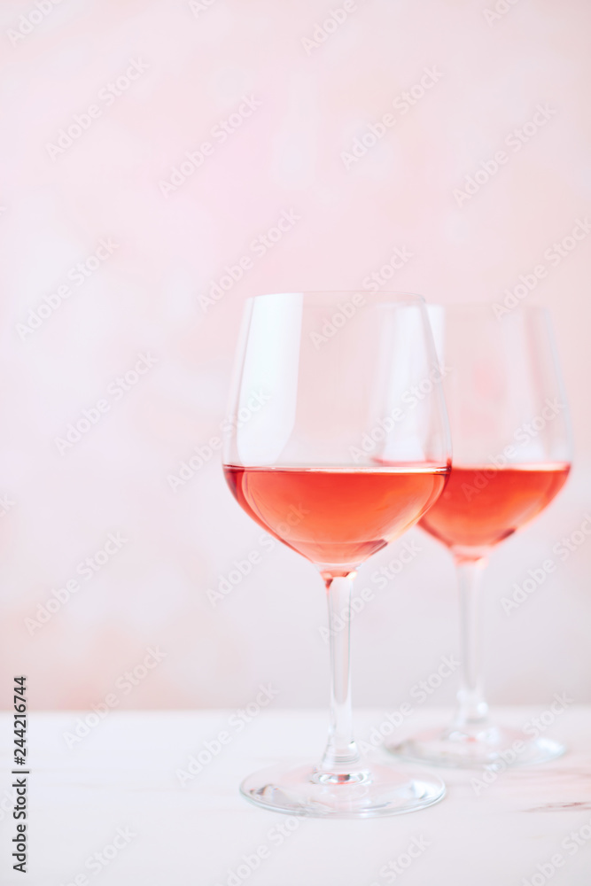 Summer drink. Glass of rose wine on white marble table over pink background with copy space for text. Selective focus. Summer drink. Glass of rose wine on white marble table over pink background with copy space for text. Selective focus.