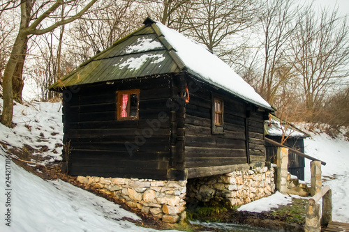 Old abandoned water mill near the lake Snowy cloudy day, sunset © Milan